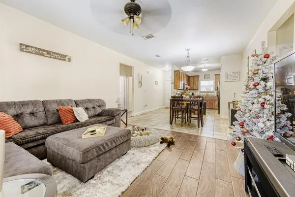 a living room with furniture and a dining table with wooden floor
