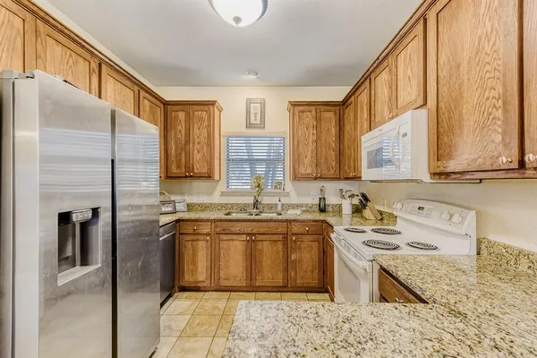a large kitchen with a stove a sink dishwasher a refrigerator and cabinets