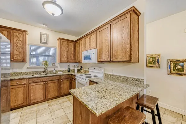 a kitchen with a sink dishwasher a stove top oven a dining table and chairs with wooden floor