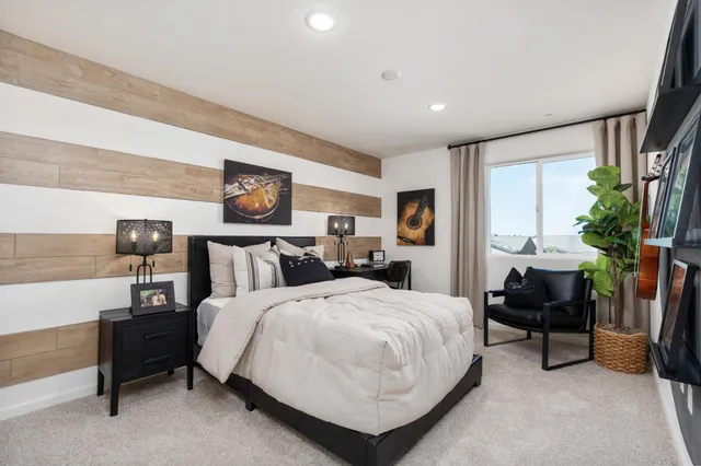 a spacious bedroom with a bed a table and potted plant on the dresser