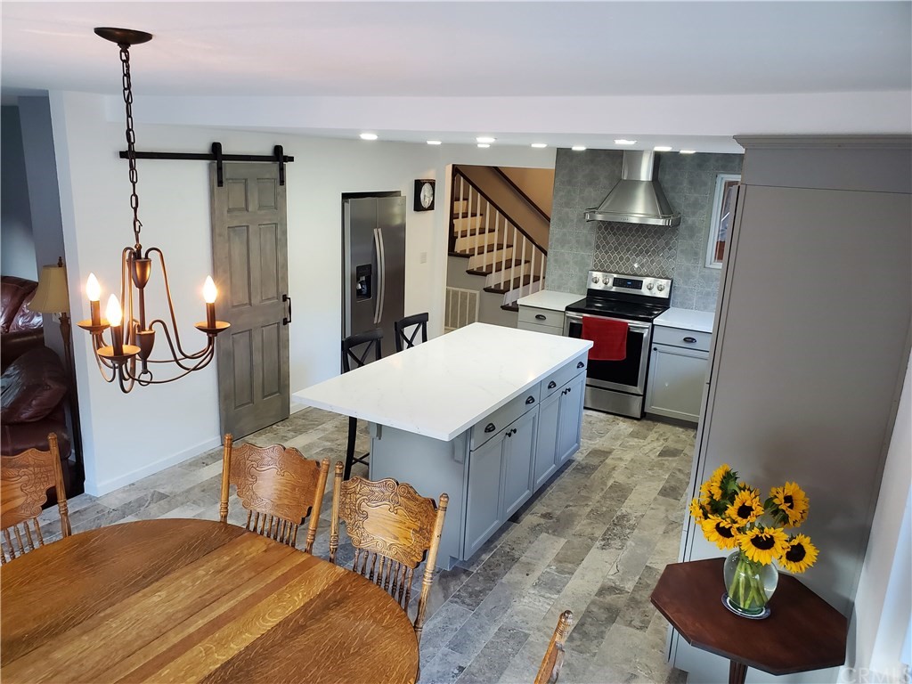 8260 Weirick Road Corona, CA 92883 - Photo 2 of 40 a kitchen with stainless steel appliances kitchen island granite countertop a refrigerator a sink a stove and a wooden floors