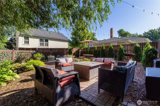 a view of patio with table and chairs potted plants and large tree