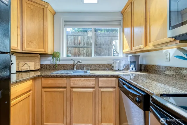 a kitchen with stainless steel appliances granite countertop a sink and a window