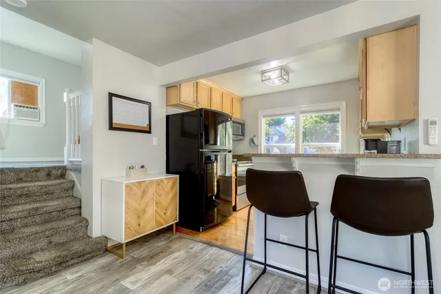 a kitchen with stainless steel appliances granite countertop a stove a refrigerator a sink a dining table and chairs with wooden floor