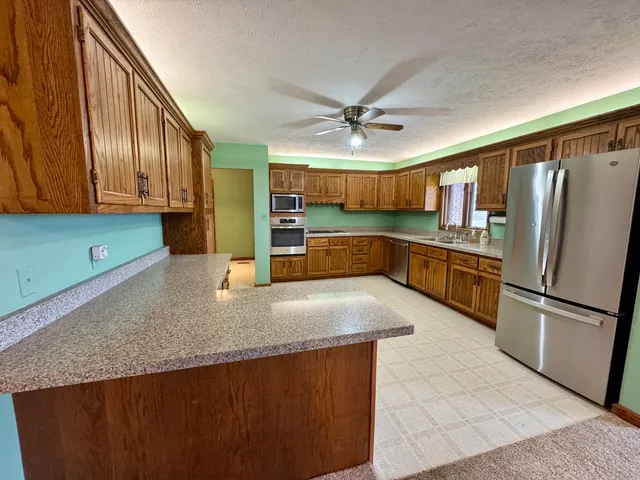 a kitchen with stainless steel appliances granite countertop a refrigerator a sink a stove with wooden cabinets
