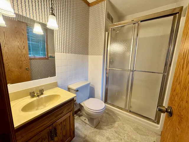 a bathroom with a sink a toilet a mirror and shower