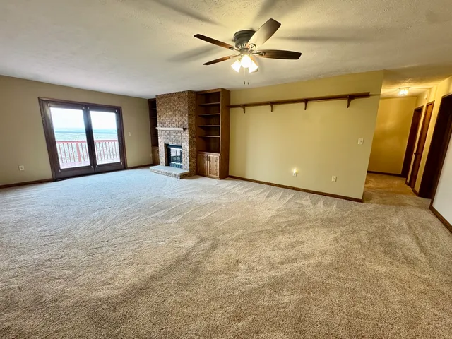 an empty room with windows and ceiling fan