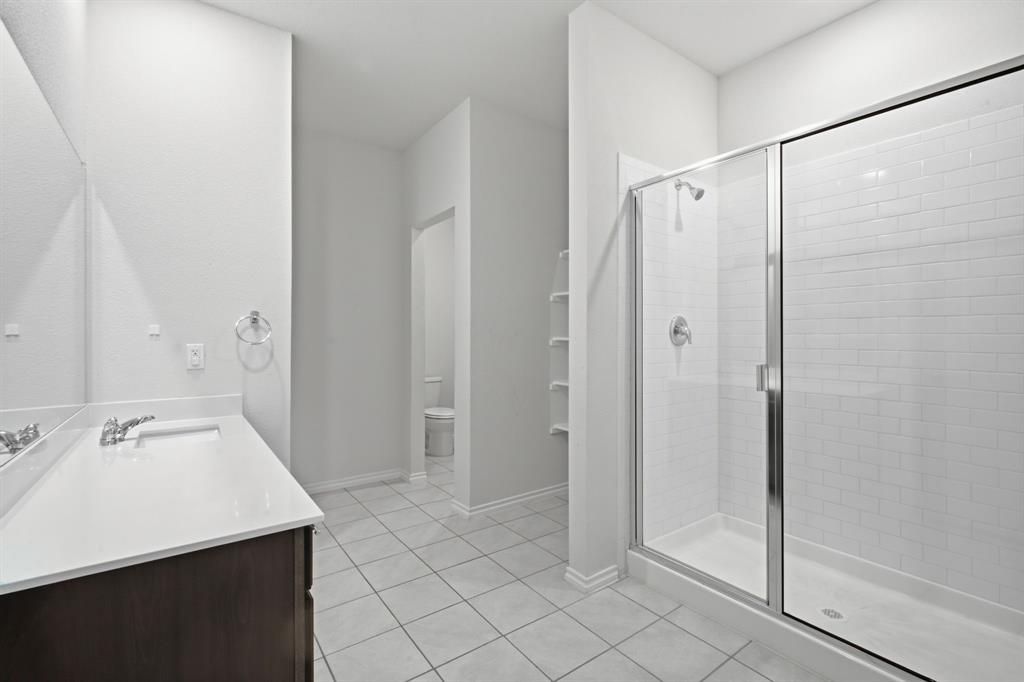 1328 Broaddus Road Forney, TX 75126 - Photo 18 of 31 Spacious bathroom featuring a glass-enclosed shower with subway tile surround, a dark wood-finish vanity with a white countertop, and tile flooring