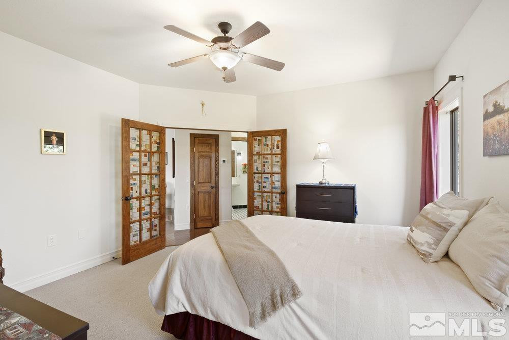 21860 Bowie Road Reno, NV 89521 - Photo 13 of 24 a bedroom with a large bed and a chandelier
