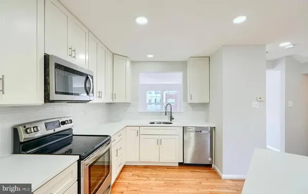 a kitchen with white cabinets and stainless steel appliances