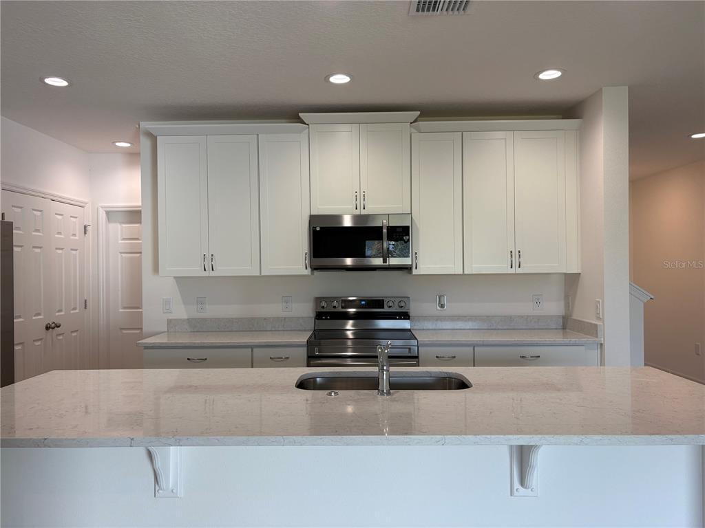 2529 Starry Point St. Cloud, FL 34769 - Photo 2 of 21 a kitchen with kitchen island granite countertop stainless steel appliances a stove refrigerator and microwave