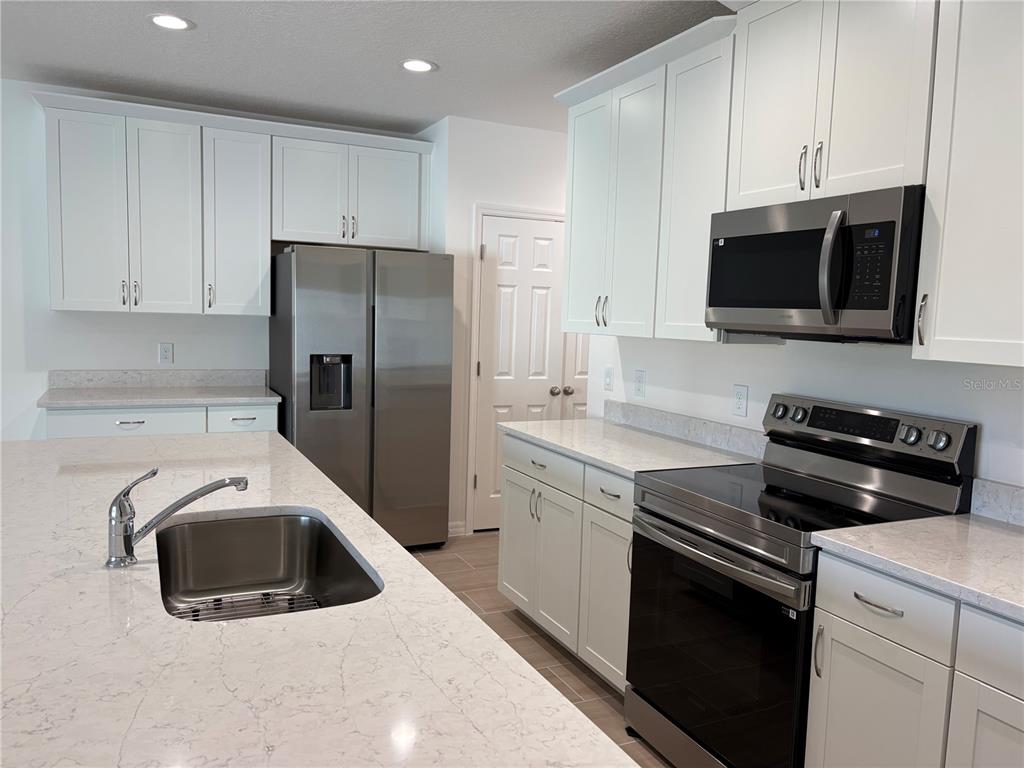 2529 Starry Point St. Cloud, FL 34769 - Photo 3 of 21 a kitchen with stainless steel appliances a stove microwave and sink