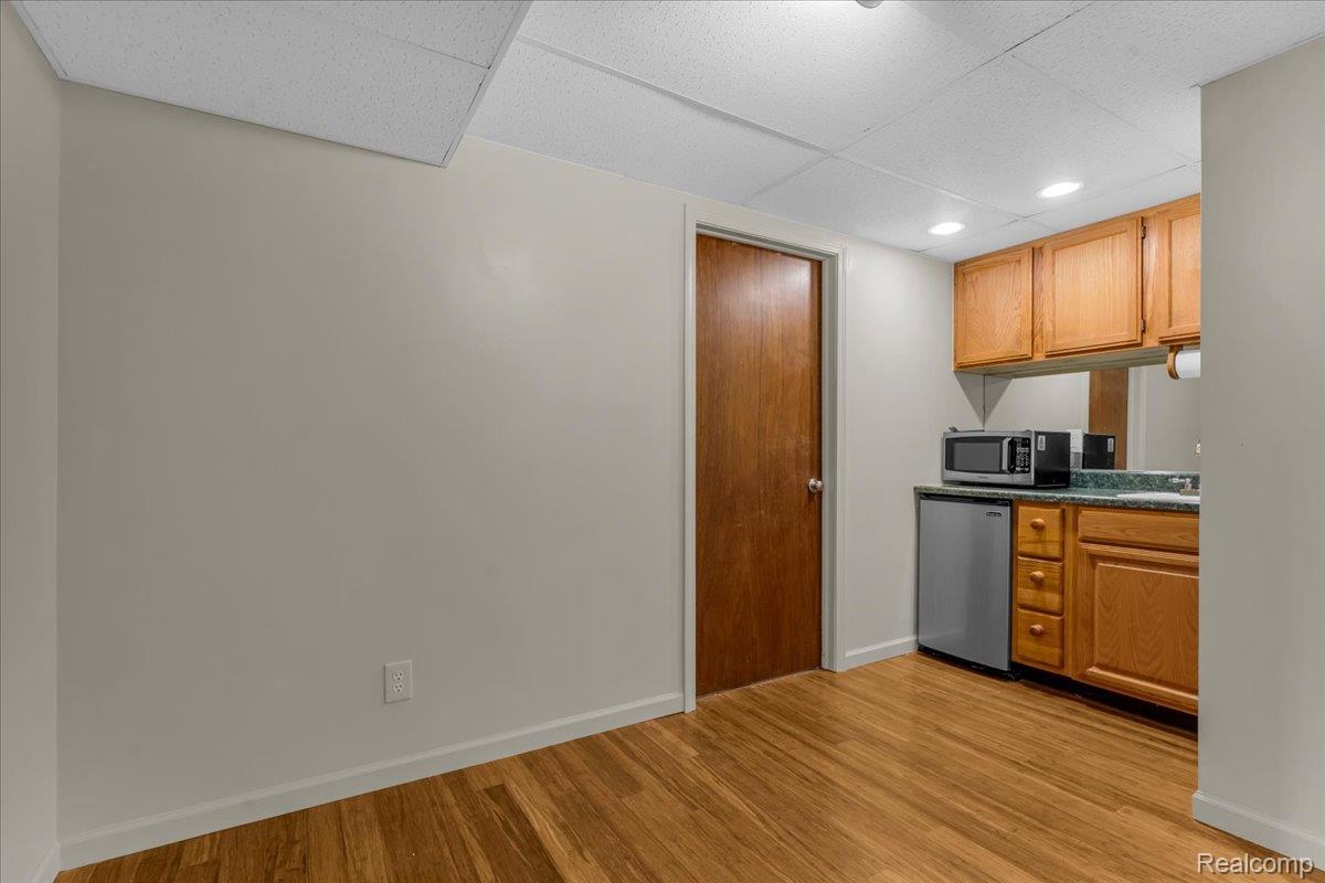 1156 Seneca Road Lake Orion, MI 48362 - Photo 20 of 50 Kitchen with a drop ceiling, light wood-style floors, brown cabinetry, stainless steel microwave, and recessed lighting