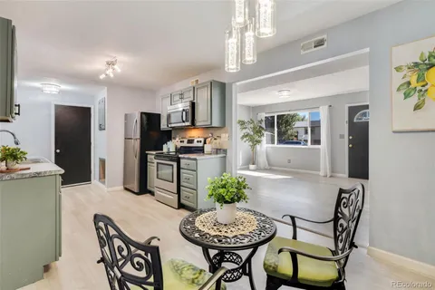 a kitchen with stainless steel appliances kitchen island granite countertop a dining table chairs refrigerator and sink