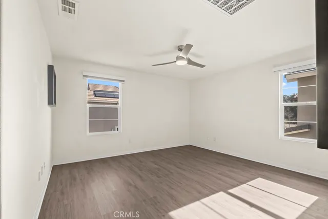 a view of empty room with wooden floor and fan