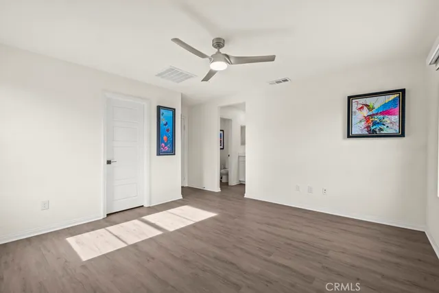 an empty room with wooden floor and ceiling fan