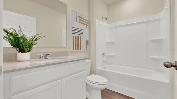 a bathroom with a granite countertop sink a toilet a mirror a vanity a bathtub and shower