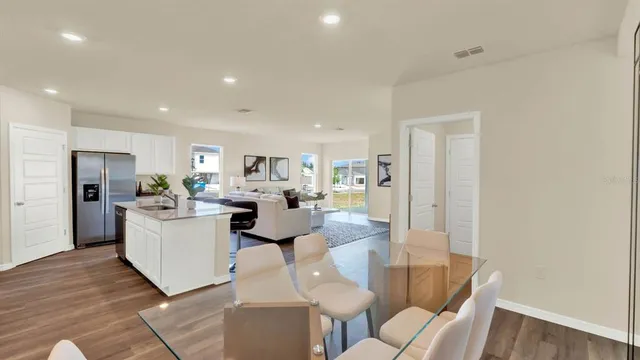 a living room with furniture a kitchen view and a refrigerator
