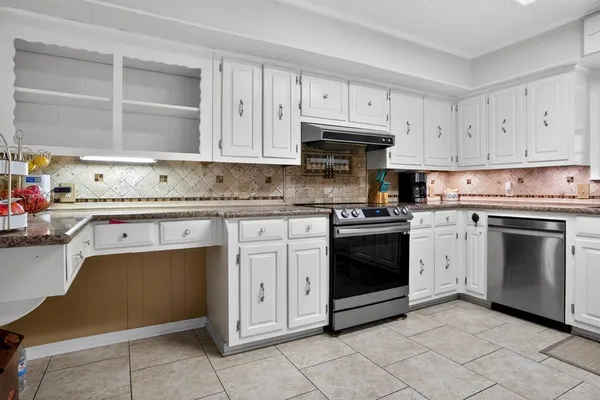 a kitchen with granite countertop white cabinets and stainless steel appliances
