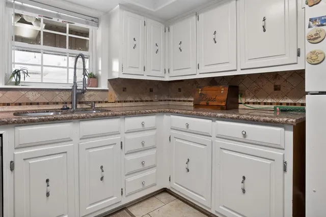 a kitchen with granite countertop white cabinets and sink