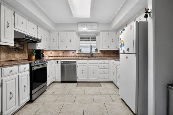 a kitchen with granite countertop a white stove top oven and white stainless steel appliances