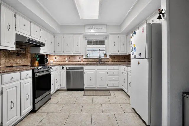 a kitchen with granite countertop a white stove top oven and white stainless steel appliances