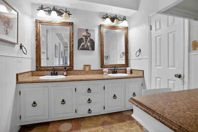 a bathroom with a granite countertop double vanity sink and mirror