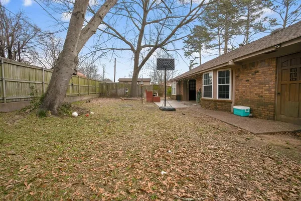 a backyard of a house with wooden fence and a large tree