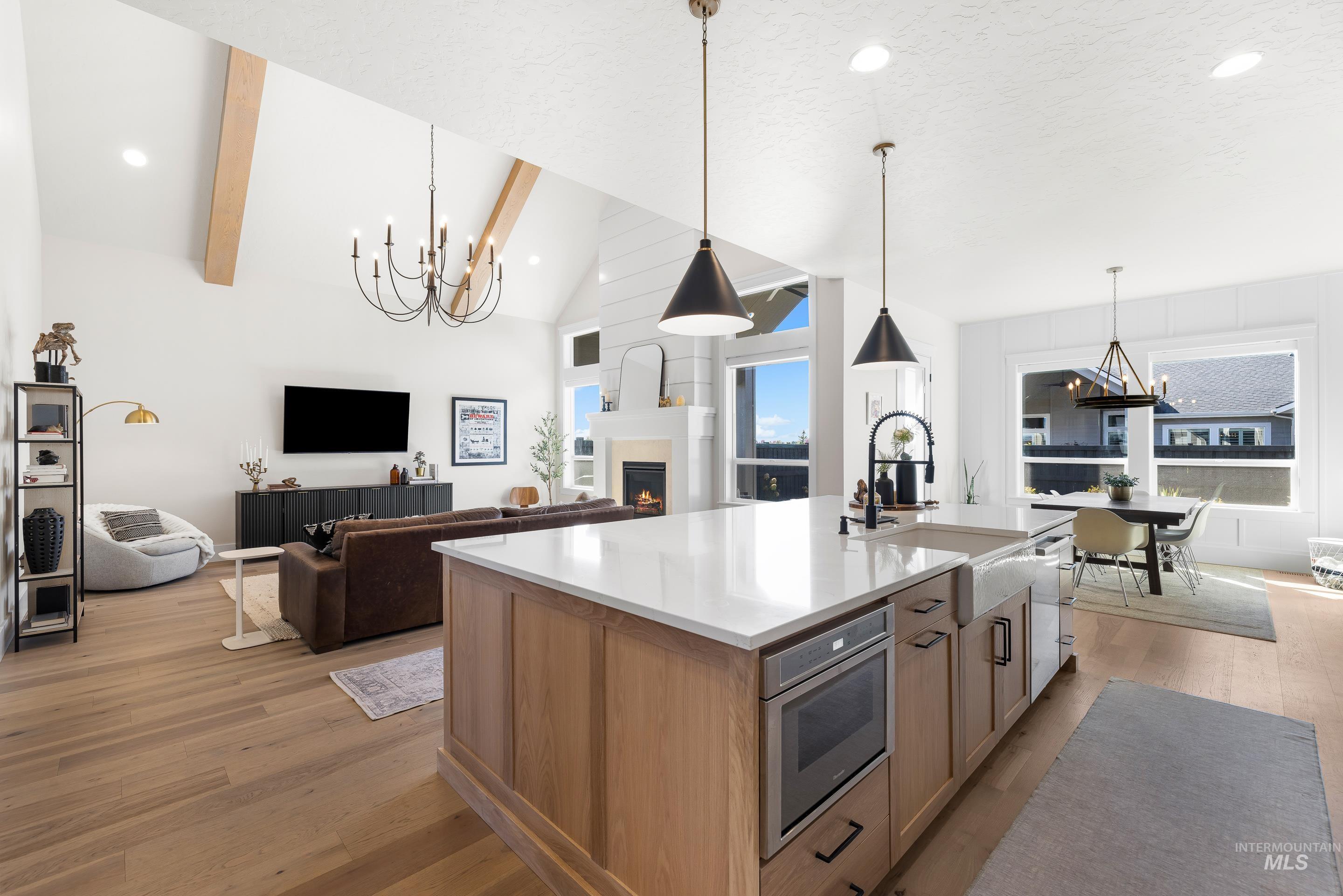 4217 North Bryant Way Meridian, ID 83646 - Photo 46 of 46 Kitchen with a chandelier, recessed lighting, light wood-style flooring, a warm lit fireplace, and open floor plan