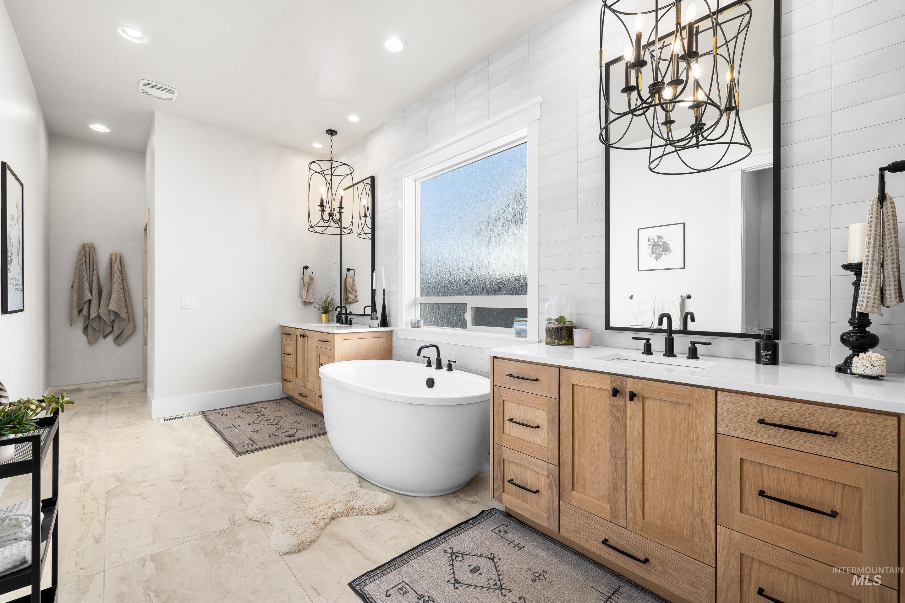 4217 North Bryant Way Meridian, ID 83646 - Photo 23 of 46 Bathroom with a chandelier, a soaking tub, two vanities, recessed lighting, and tile walls