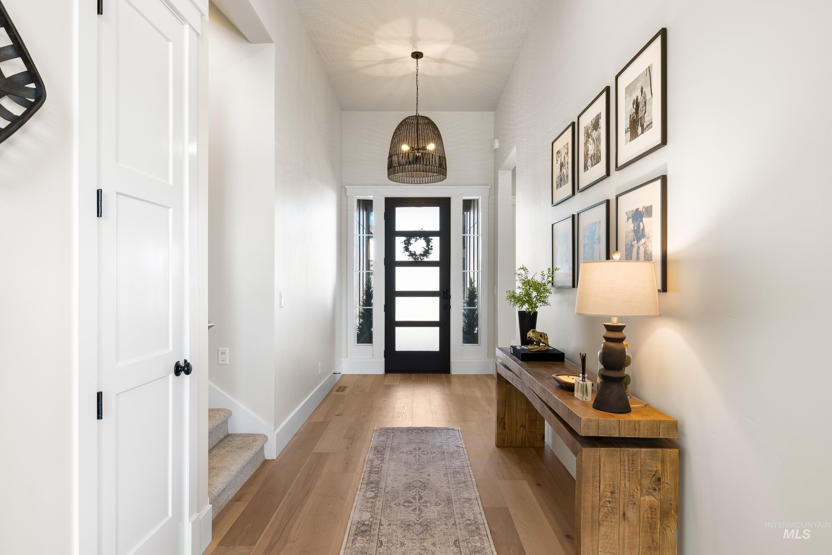 4217 North Bryant Way Meridian, ID 83646 - Photo 4 of 46 Entryway featuring light wood-style floors, a chandelier, stairs, and a towering ceiling