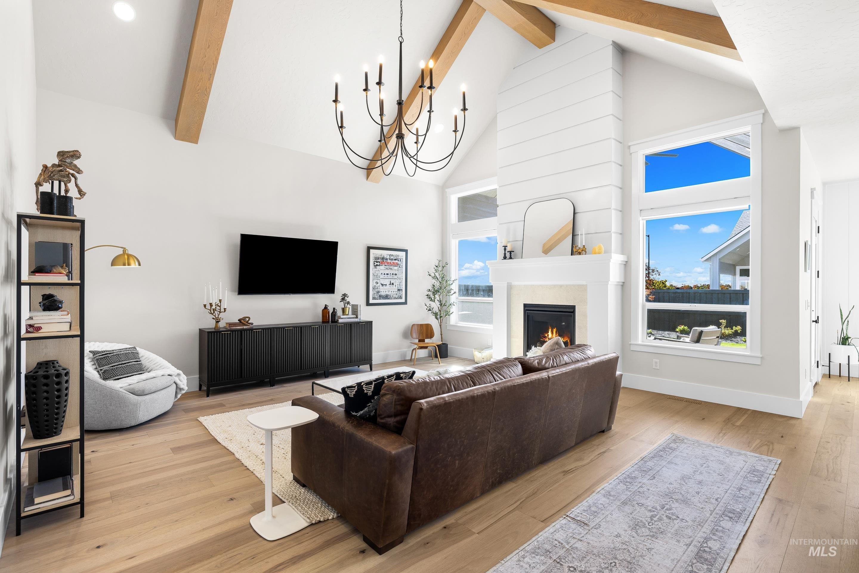 4217 North Bryant Way Meridian, ID 83646 - Photo 7 of 46 Living room with beam ceiling, high vaulted ceiling, a large fireplace, a chandelier, and light wood-style flooring