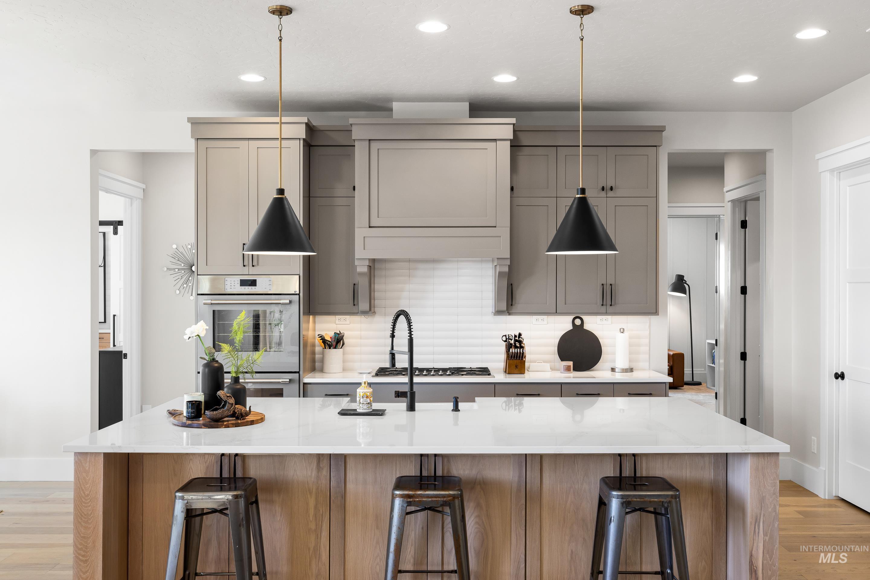 4217 North Bryant Way Meridian, ID 83646 - Photo 10 of 46 Kitchen with light wood-type flooring, tasteful backsplash, recessed lighting, and a kitchen island with sink