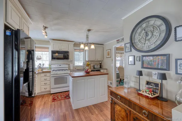 a kitchen with stainless steel appliances a stove top oven a refrigerator cabinets and a dining table