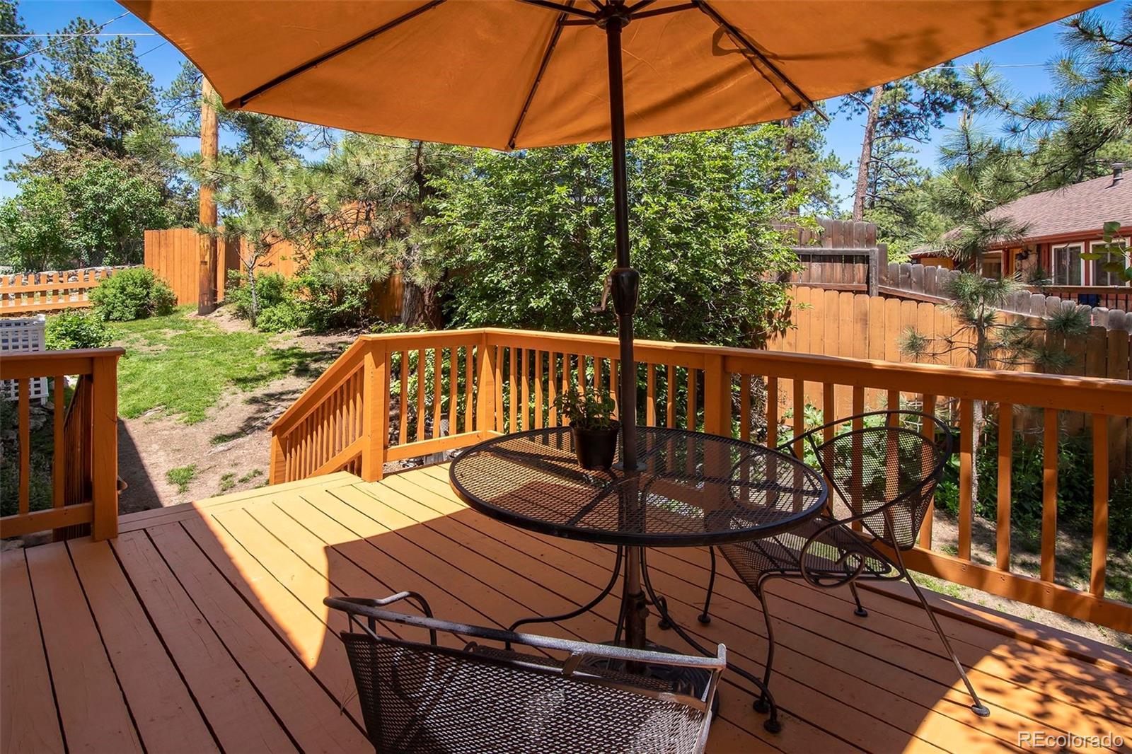 4805 Blue Spruce Road Evergreen, CO 80439 - Photo 18 of 43 a view of a roof deck with table and chairs under an umbrella with wooden floor and fence