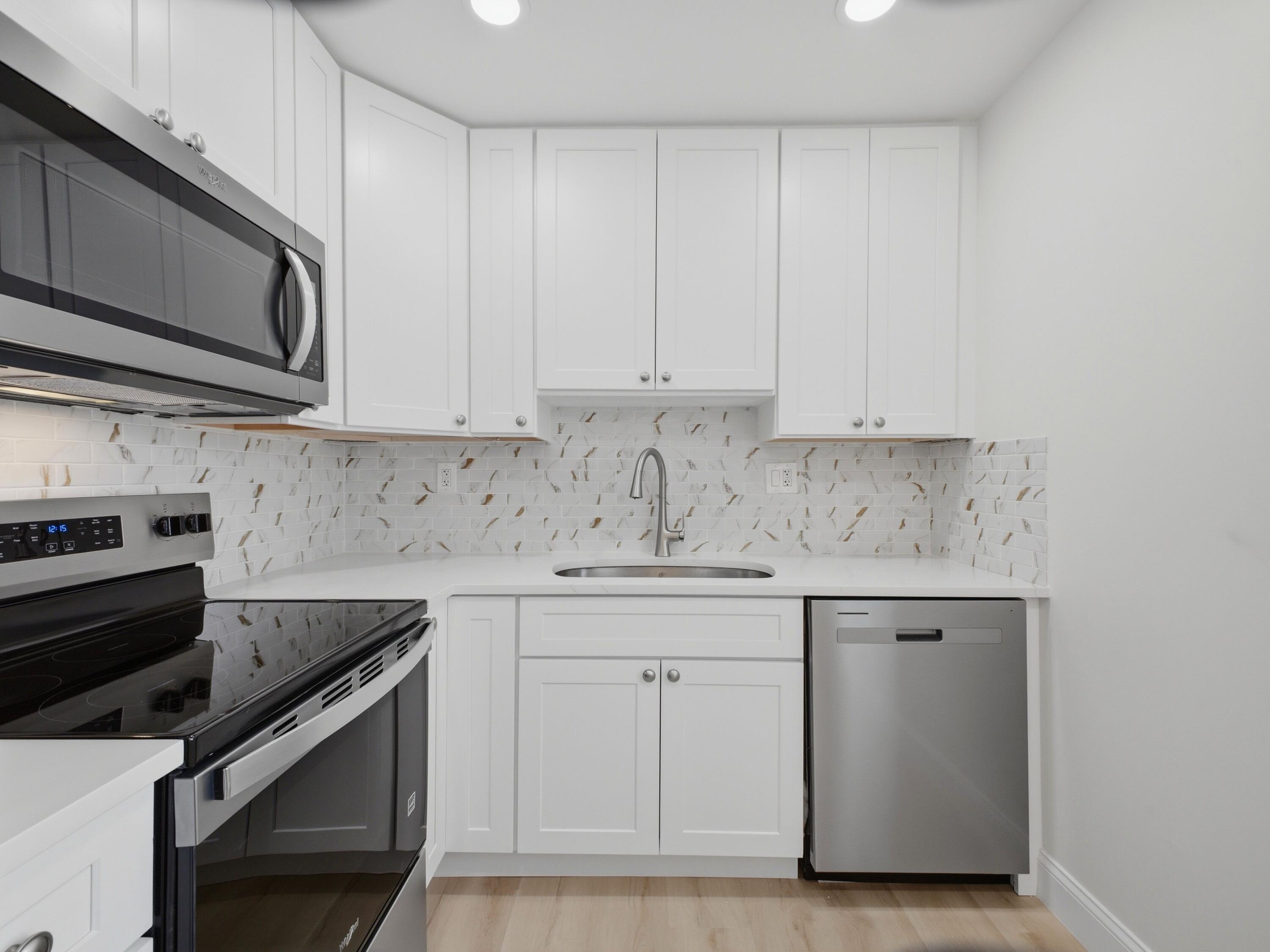 699 Flanders O Delray Beach, FL 33484 - Photo 1 of 39 a kitchen with granite countertop white cabinets and stainless steel appliances