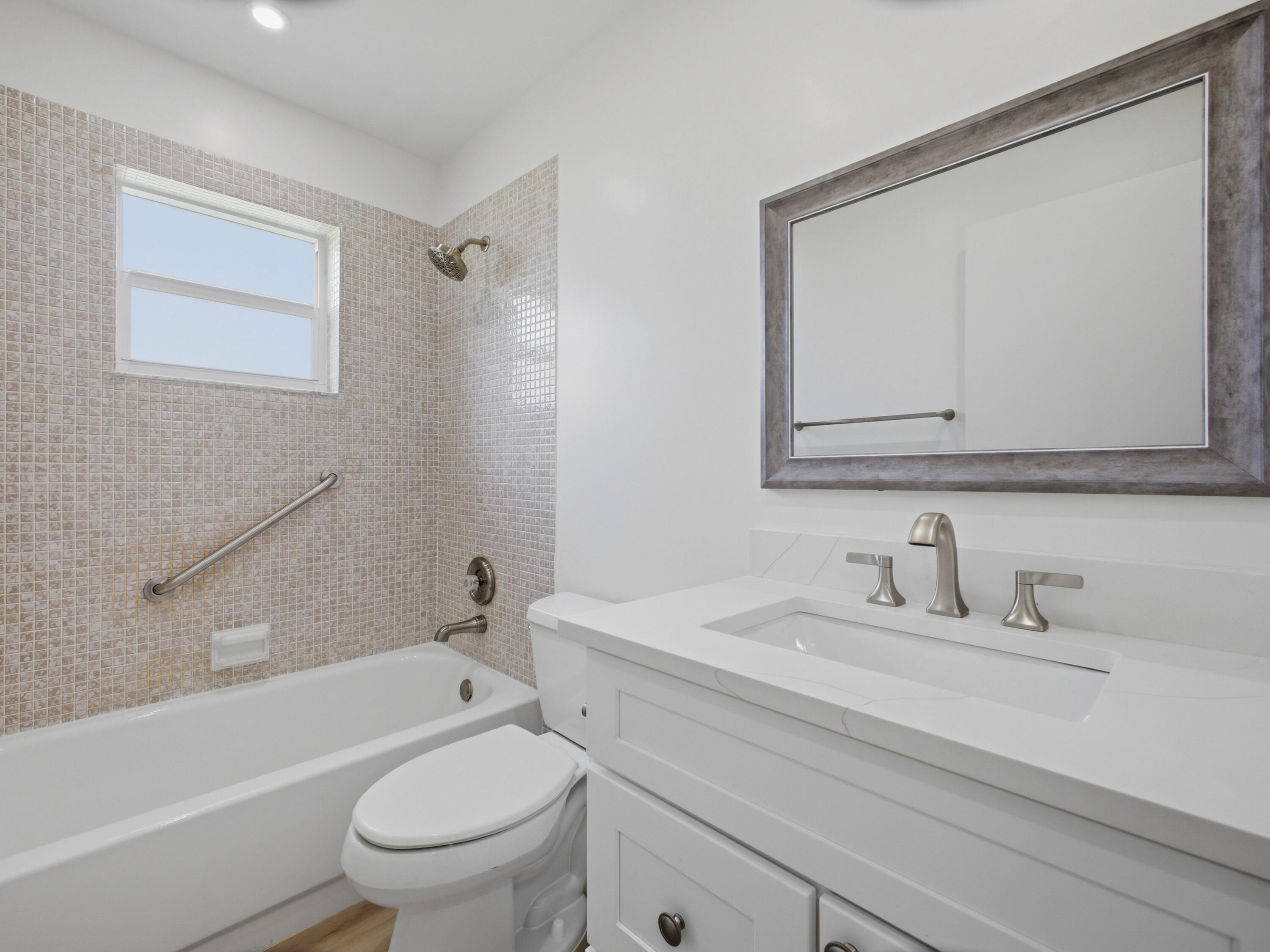 699 Flanders O Delray Beach, FL 33484 - Photo 14 of 39 a bathroom with a toilet a sink a mirror and a bathtub