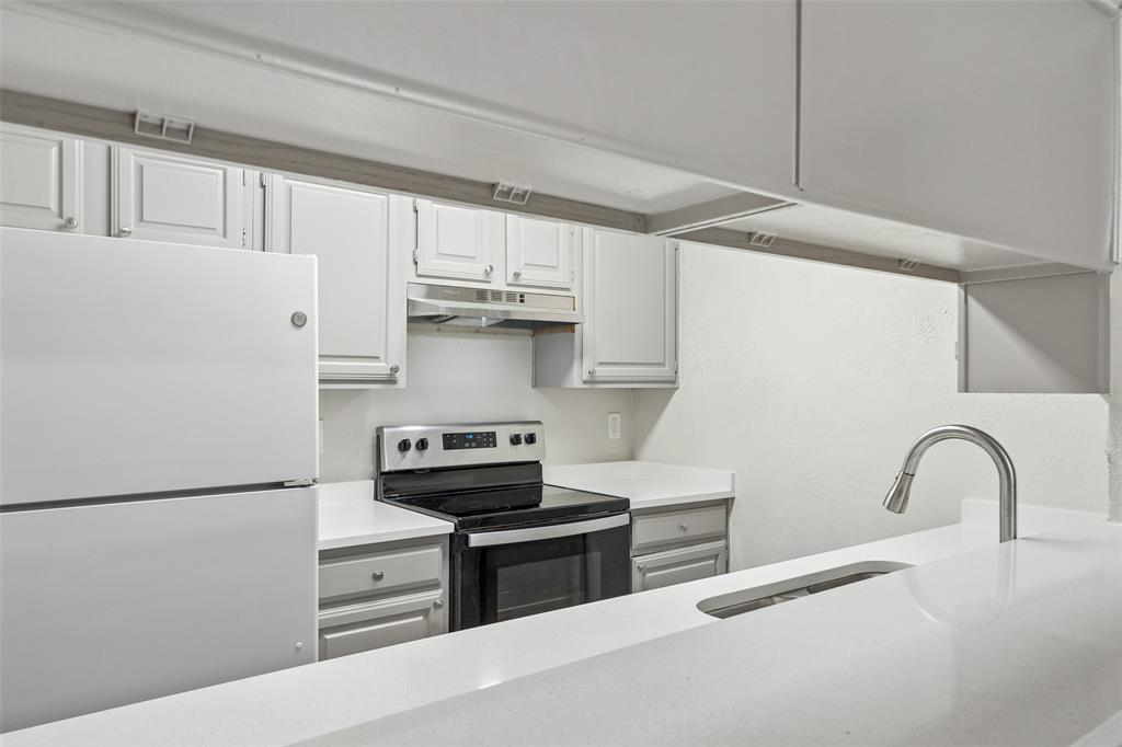 11480 Audelia Road, Unit 136 Dallas, TX 75243 - Photo 20 of 29 Contemporary kitchen featuring light-toned cabinetry, stainless steel appliances, a bar-height countertop with an integrated sink, and an arched pull-down faucet