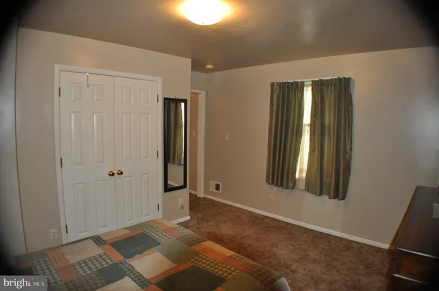 a view of an empty room with window and closet area