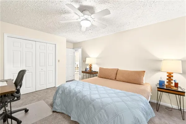 a bedroom with a bed a chair and potted plant on the dresser