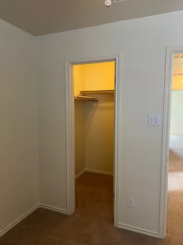 a view of an empty room with closet and a window