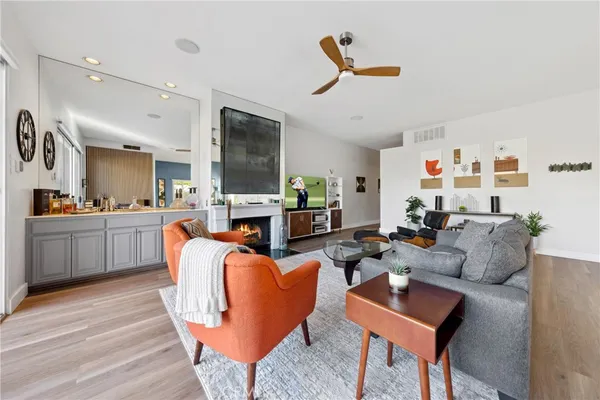 a living room with furniture kitchen view and a wooden floor