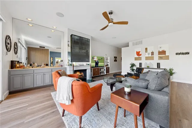 a living room with furniture kitchen view and a wooden floor