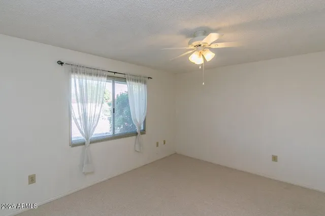 an empty room with windows and fan