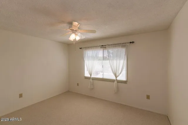 an empty room with a window and a fan