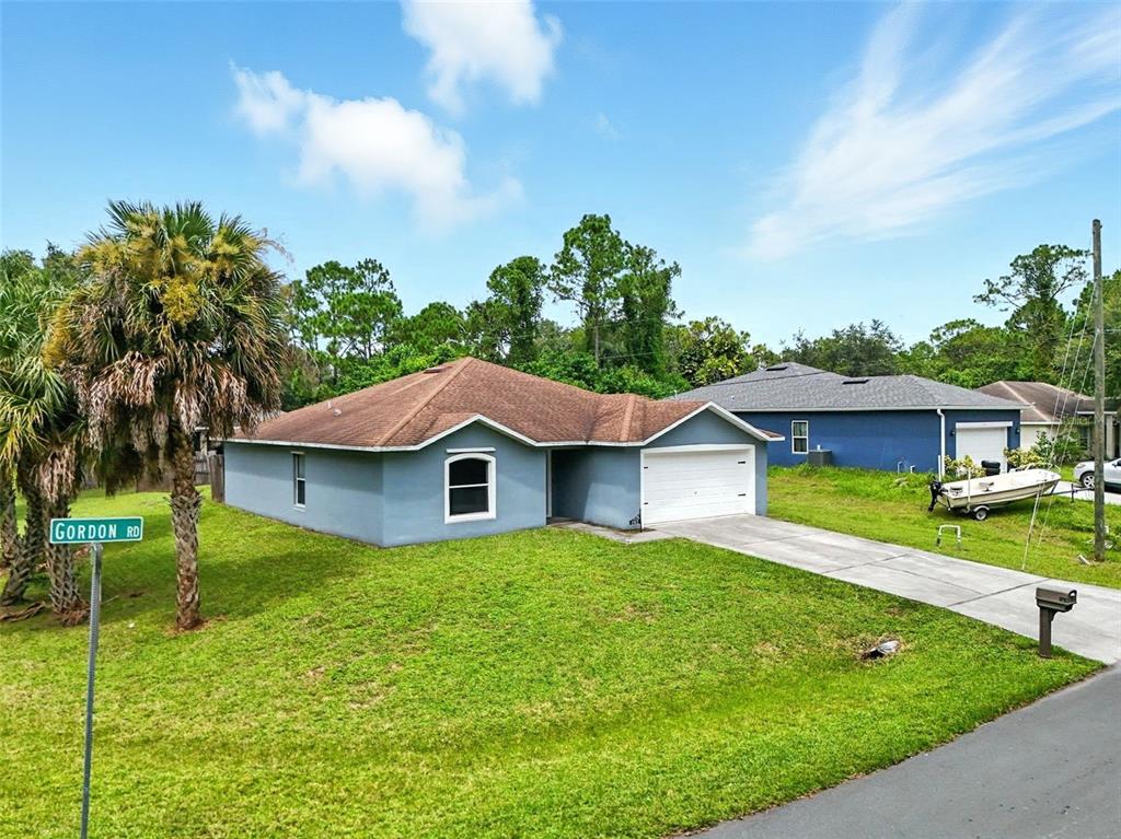a view of a house with a big yard plants and large trees