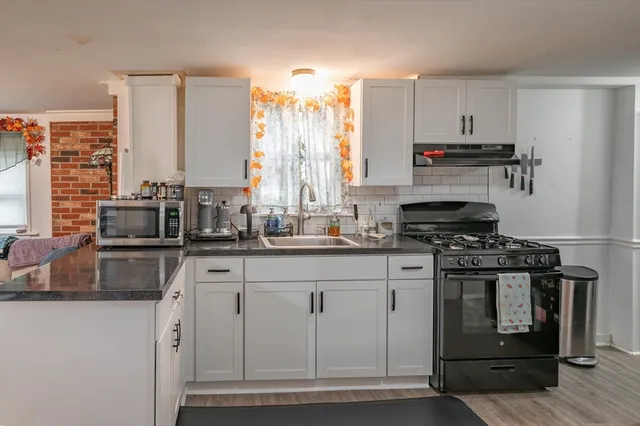 a kitchen with stainless steel appliances a stove a sink and white cabinets