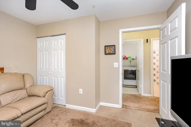 a living room with furniture a refrigerator and a flat screen tv