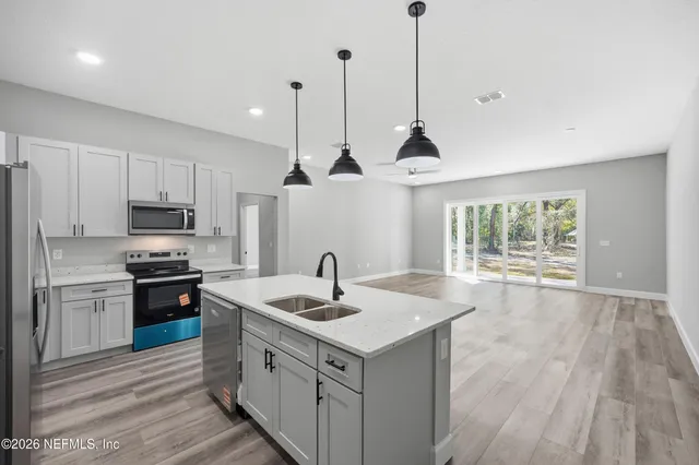 a kitchen with a sink stove and wooden floor
