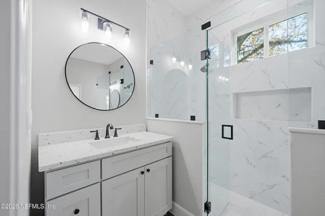 a bathroom with a sink a mirror a vanity and a shower